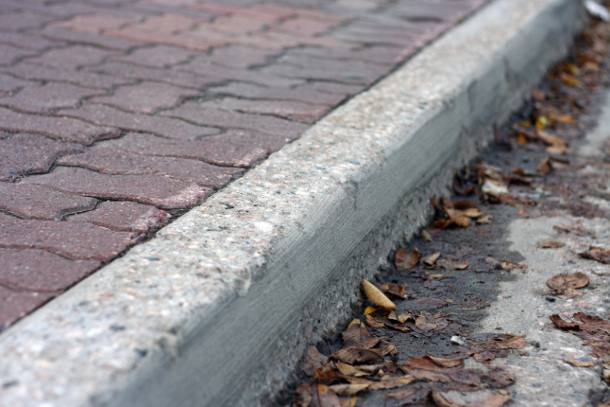 A simple design for a powerful use, the modern curb serves as separation of pedestrians from vehicles, people from water and waste, upland from lowland, and public from private. The movement of waste to the edges from the adjacent sidewalk and roadway is visible in the collection of leaves and debris in the gutter. Photo Source: Wikipedia