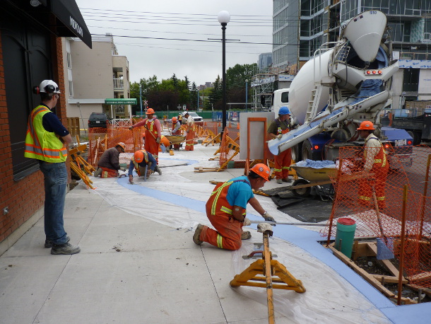 A decorative ribbon of blue concrete indicates that this stretch of 2nd Avenue is different. Here, the concrete is being poured.